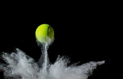 A tennis ball bouncing in chalk dust with black background. Conceptual, signifying ball hitting the line
