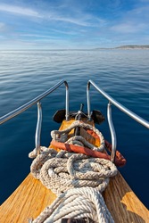 the bow of a traditional wooden boat with teak deck, hardwood bowsprit with blue sea and blue sky behind