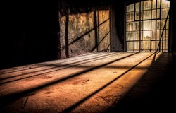 Sun rays fall through tall windows into an abandoned dusty room. Sunlight window in darkness. Dark sunlight window. Tall window sunlight
