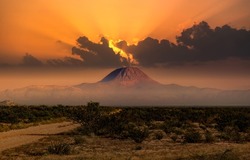 A mountain in the distance in the fog of sunset. Sunset mountain peak landscape. Mountain peak at sunset