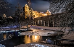 Winter night over the castle walls. Medieval castle in winter night. Ice lake at winter castle walls into the night