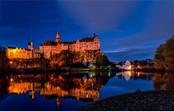 The castle is reflected in the night water of the lake. Castle lake into the night. Night castle lake view
