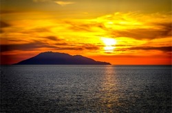 Silhouette of the island at sunset. Sundown sea landscape. Sundown sea at sunset. Beautiful sunset sky over cloudy sky