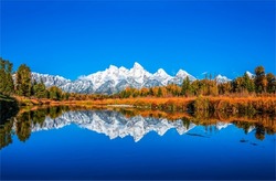 Snowy mountain peaks are reflected in the lake water. Mountain lake water reflection. Lake in mountain valley. AUtumn mountain lake landscape