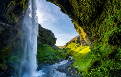 Waterfall streams in the green mossy mountain arched cave