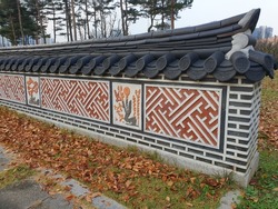 Korean traditional style of walls. A wall with geometric and Korean patterns and symbolic sculptures. Korean tile roof. A Korean wall outside.