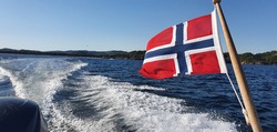 Norwegian flag waving in the wind on 17 may constitution day on a boat in the archipelago of southern Norway