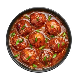 Veg Manchurian Gravy Balls in black bowl isolated on white. Vegetarian Manchurian is indian chinese cuisine dish. Asian food and meal. Top view