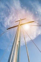 Bottom view mast boat against sky with cumulus clouds in sea. Mast of sailing yacht with ropes without sail at blue sky background. Transportation, cruise, sailing, yachting concept. Copy space