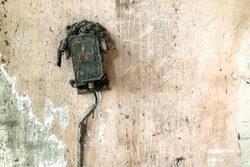 Background of electricity meter on ruined filthy wall. Abandoned rusty electric power distribution box on dirty textures wall in industry building. Concept of old equipment. Copy text space