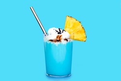 Pina colada cocktail with a slice of juicy pineapple and foam of whipped cream, melted chocolate and metal eco straw. alcohol-free like a milkshake on blue background. Traditional caribbean cocktail