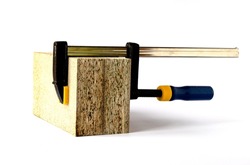 Two samples of chipboard are clamped with a carpenter's clamp on a white background