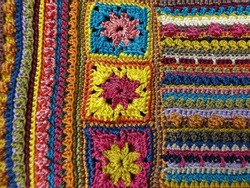 Image of colorful surface of crochet fabric. Made of yarn, mixed stitches. Concept of art, creativity, and craftsmanship. Focus selection. 