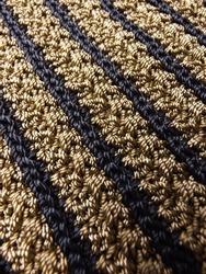 Texture of crocheted fabric in brown and black yarn in diagonal direction. Focus selection.