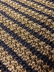 Texture of crocheted fabric in brown and black yarn in diagonal direction. Focus selection.