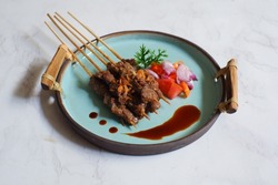 selective focus of a plate of beef satay or sate maranggi in Bahasa against white background