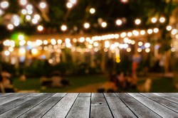empty grey wooden floor or wooden terrace with abstract night light bokeh of night festival in garden, blurred background, copy space for display of product or object presentation, vintage color tone