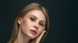 Depressed young woman. Close-up studio shot of beautiful teenage girl with delicate makeup posing against black background