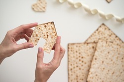 Woman's hand holds Matzah shape of house. Traditional of Jewish Holiday on Passover. Home symbol of lovely family. top view, layout. real estate agency