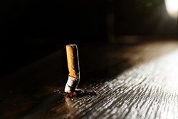 A smoking burning cigarette on a dark floor background. Stop smoking concept