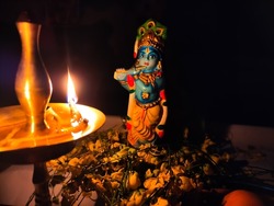 Idol of god krishna shining with a lamp light. The background is black and blurred. Photo taken with low light.