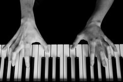 hands play the piano. black piano. white and black keys