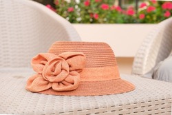 pink wicker women's hat with a flower decoration lies on an table. Close-up detail of summer female wardrobe. Sea vacation symbol, hot day