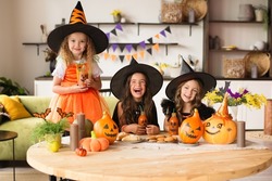 children in Halloween costumes with a pumpkin are fooling around at the holiday, having fun and playing, a witch dress and a hat, a decorated house
