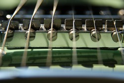 Macro shot of 6 string electric guitar strings and pickups, focus on the strings. Detail of electric guitar strings. Vintage light green guitar.