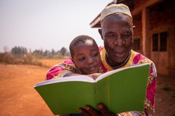 African grandfather reads a book with his grandson, moment of love and tenderness between them. Concept of grandfather educating his grandson