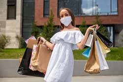 girl in medical mask with purchases near the shopping mall