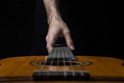 Guitar on a black background. Acoustic guitar on a dark background. Man's hand reaches for the guitar