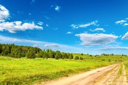 Summer green rural dirty road between green grass hills scenery landscape sunny day