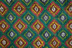 Handmade multicolor carpet with rhombus ornament, braided mat, closeup, texture background.