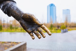 Male hand palm bronze sculpture in rain gives hand, help concept. Close-up