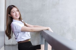 Portrait of an adult Thai student girl in university student uniform. Asian beautiful girl sitting smiling happily at university