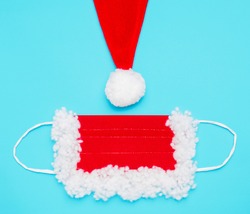 protective mask and part of a hat with a pompom for Santa Claus, red and white, on a blue background