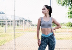 Young woman rests after jogging. Caucasian female fitness model working out in the morning. Fit young woman standing after workout. Female athlete resting after training session. Fit girl resting