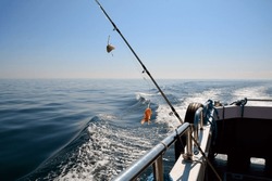 A spinning rod for catching fish with shrimp bait is rigged on board the fishing boat.