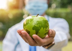 World health day, an apple a day keeps the doctor away concept for health benefit by eating high nutritious clean food and healthy nutritional diet with doctor handling green apple giving to patient