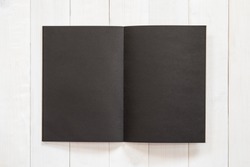 Blank A4 size black book template mock up with open double page placing on creamy white surface wood  table
