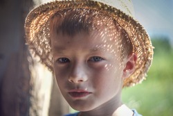 smiling boy with gray eyes and freckles in a straw hat.  close-up
