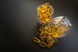 2 glasses of fish oil capsules with black background 