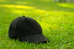 Black textile cap on green grass, background blur, space for text