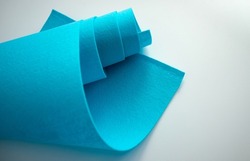 Blue felt fabric on white isolate. Sale of fabric in the store and in the warehouse. Sea-green felt. The fabric is twisted into a roll.