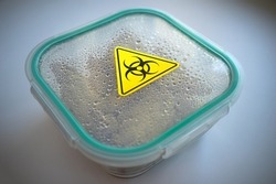 A plastic container with a yellow radiation sticker.contaminated food. Danger of poisoning. A deadly poison in a container.Poisoned food.