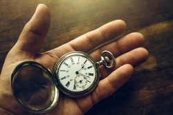 Vintage pocket watch is in your hand.A man's hand holds a vintage mechanical watch on a wooden background. The passing time.