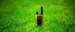 The yellow walkie-talkie is standing in the grass. Radio for transmitting a signal over distances.A yellow radio station with a black antenna in the field.
