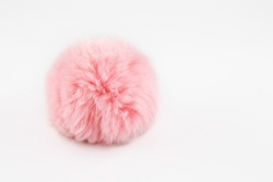 A fluffy ball of pink faux fur on a white background. Pompon. A toy for a cat. Decoration and decor of clothes. Eco-fur ball, soft and pleasant to the touch