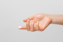 A drop of thick white hand cream on the finger of a woman's hand. Groomed hands, natural short nails, on a light background.